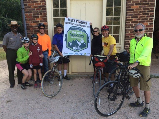 A group of bicyclists pose by a park building