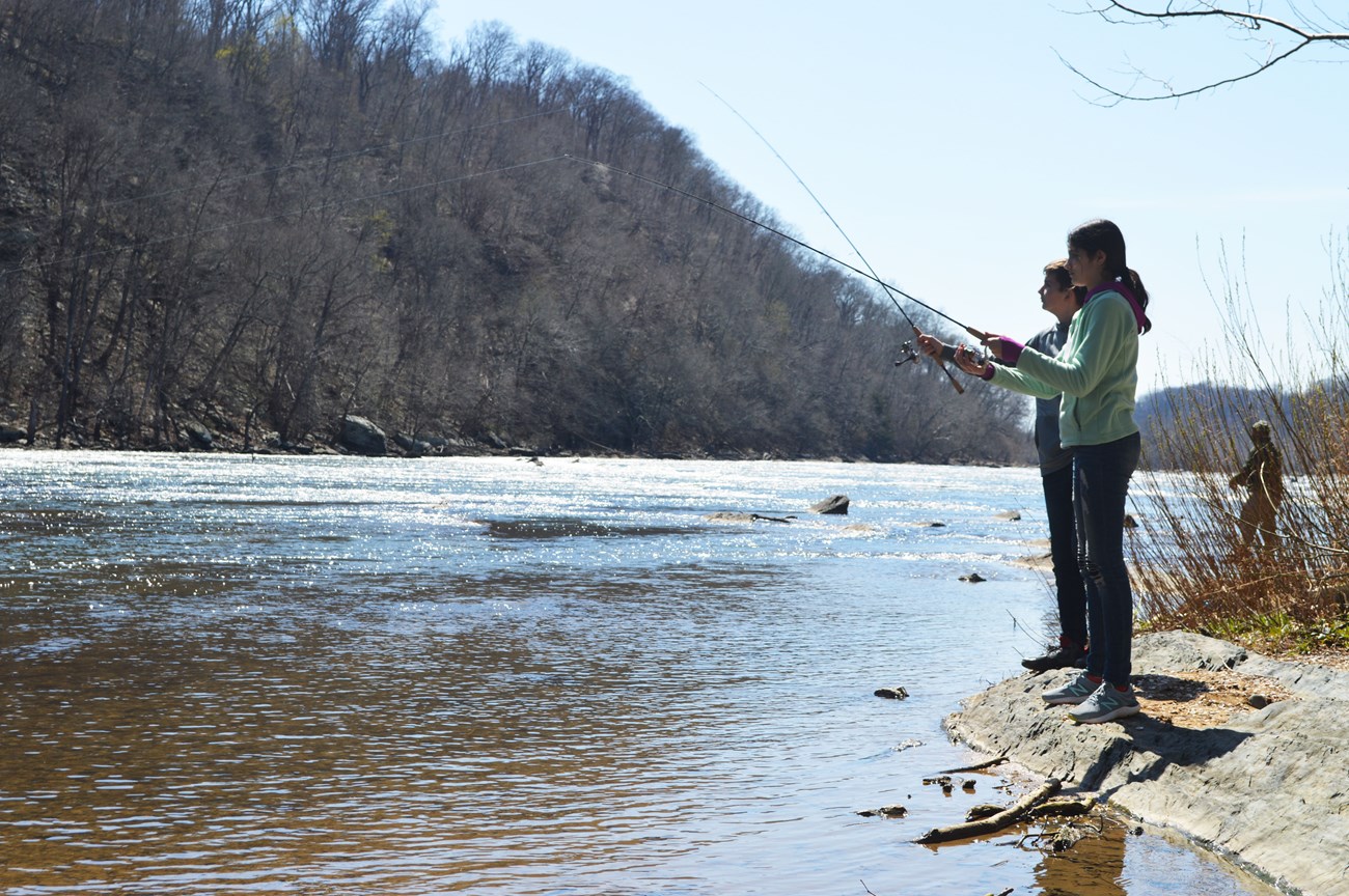 Girl and boy fishing from the river bank