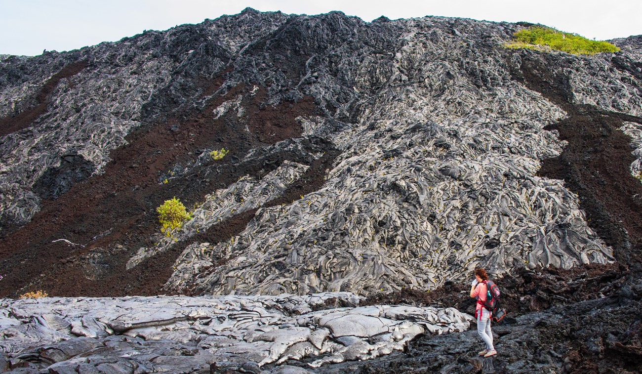 A person stands next to solidified lava flows