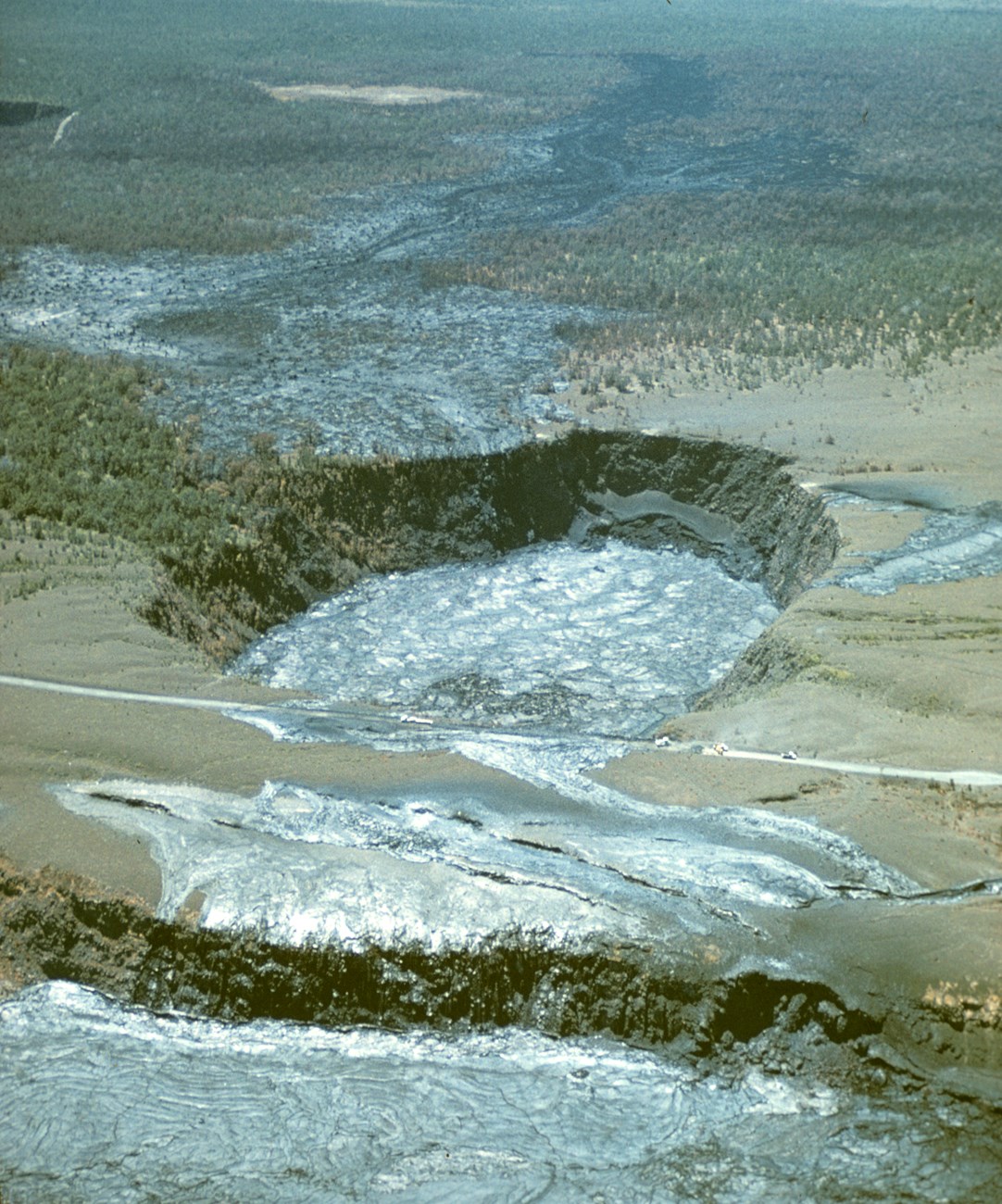 Aerial view of solidified lava flows near a pit crater, crossing a road into a larger caldera