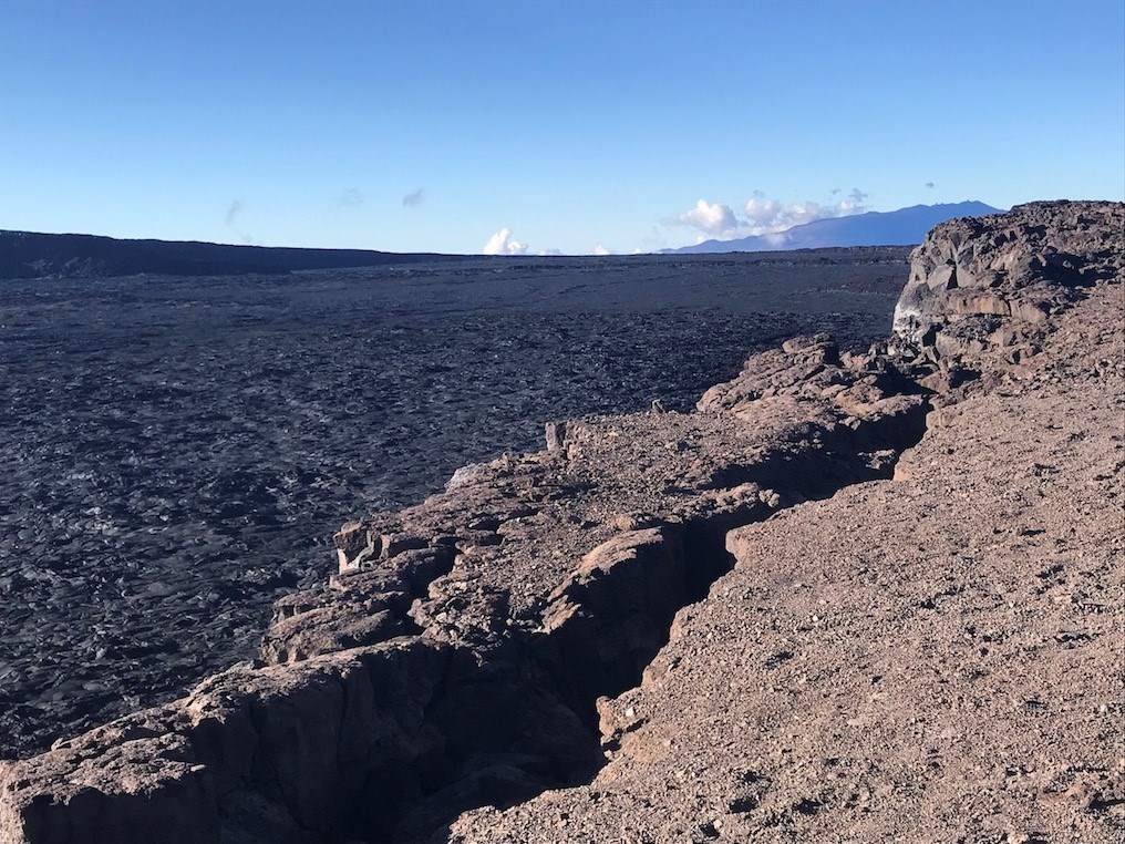 A large volcanic crater with a mountain visible in the distance