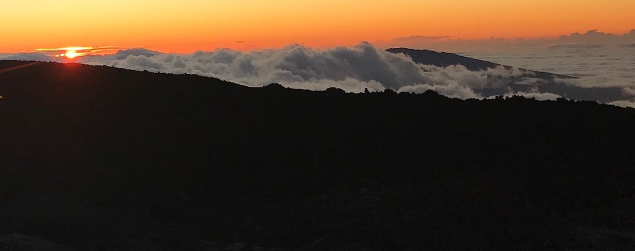 A mountain peak shows through clouds at sunset