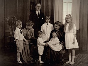 A portrait of a family seated and standing in a paneled room.