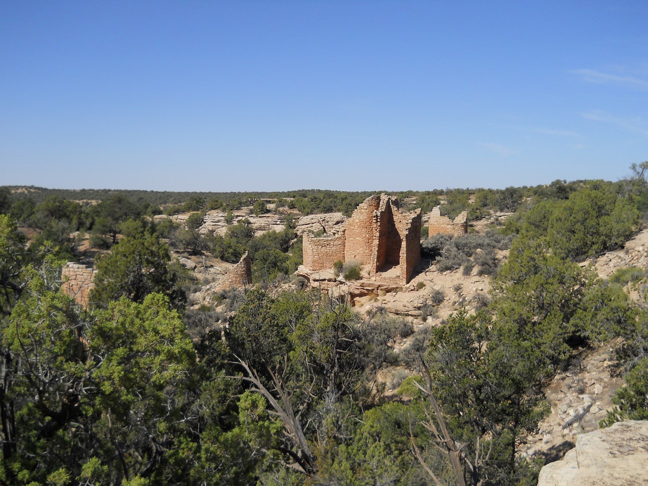 remains of a large stone structure perched on a boulder, surrounded by trees