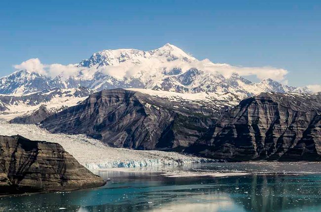 A panorama of the Chugach Mountains with a tidewater glacier and Mt St Ellias in the background.