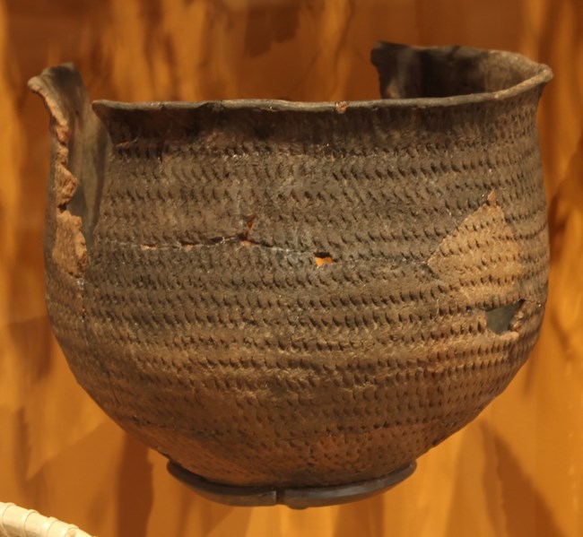 Paiute pottery served everyday needs—cooking, storage, and survival in the desert. Worn clay pot with textured surface and visible cracks and repairs.