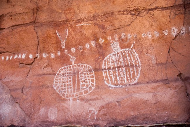 Peekaboo Rock Markings NPS Neal Herbert White pictographs on red sandstone wall at Peekaboo in Canyonlands National Park.