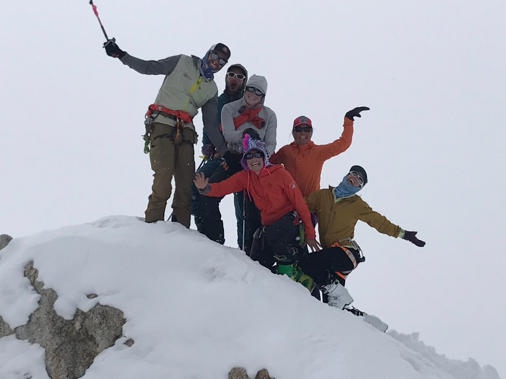 Six patrol members pose on a snowy rock outcropping