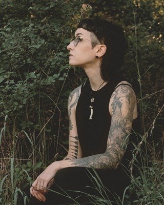 photograph of artist sitting amongst grasses and shrubs