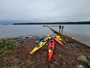 Kayaks lay on the beach at Daisy Farm dock on an overcast day.
