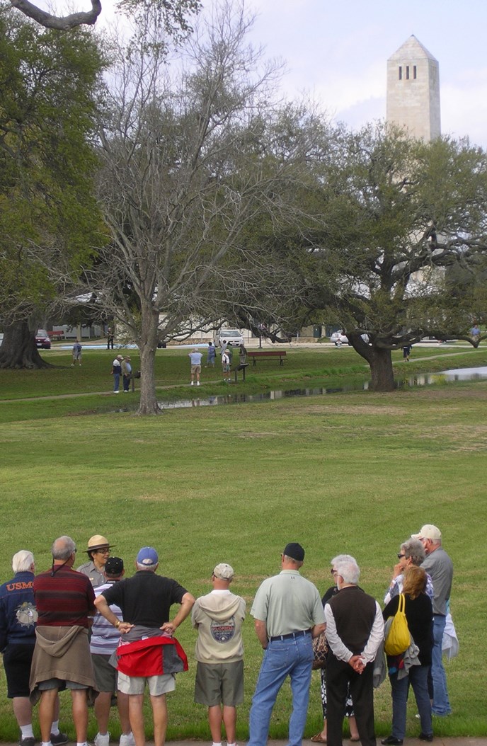 Image of park ranger talking to people with Chalmette Monument in background