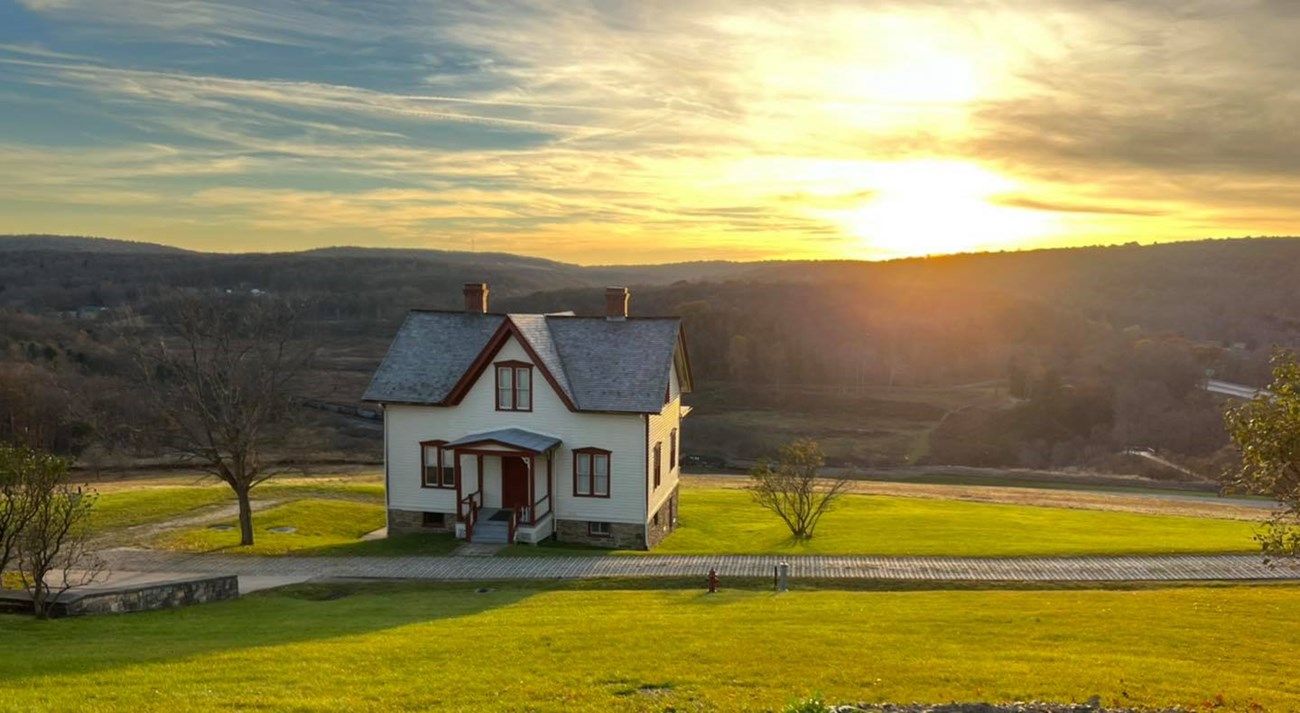 A farm house with the remains of the dam in the background.