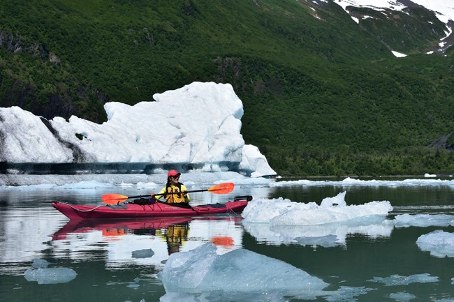 A kayaker with icebergs beyond