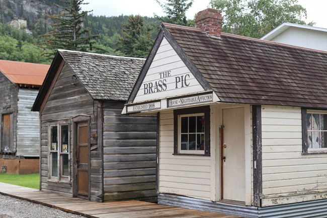 Two small wooden peek roofed buildings side by side