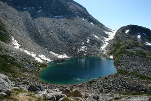 Small body of water surrounded by loose rocks and a mountain