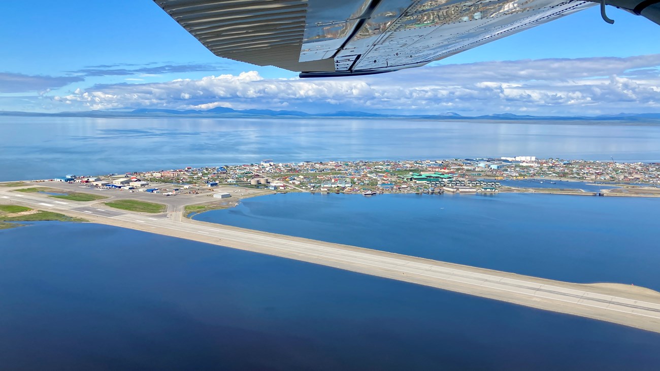 Village of Kotzebue as seen from the air. View is to the north with blue waters and distant clouds.