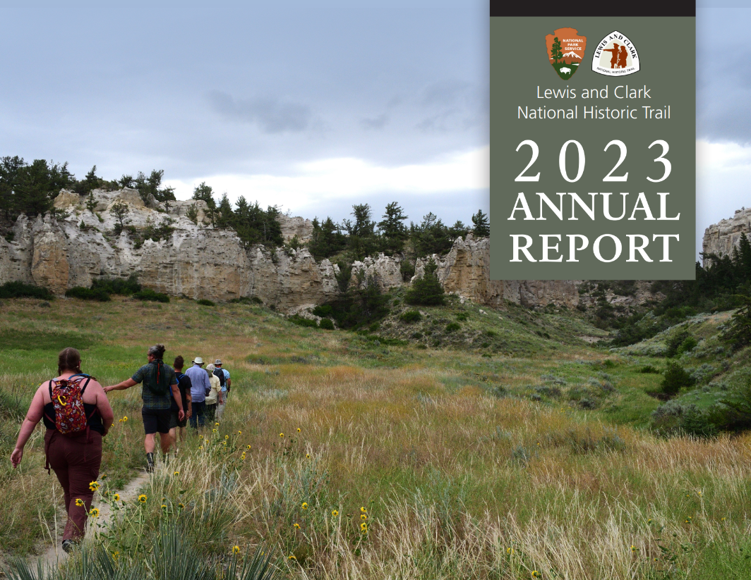 Group of people walking through a tallgrass field towards tall forested cliffs