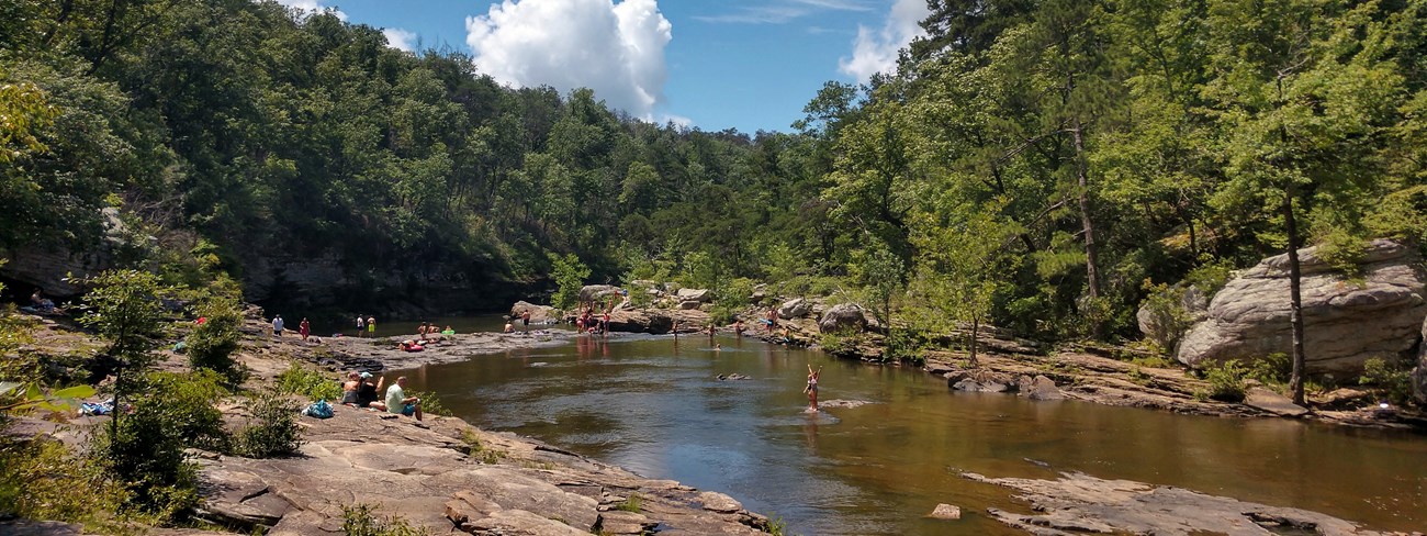 People enjoying the river along the rocky riverside