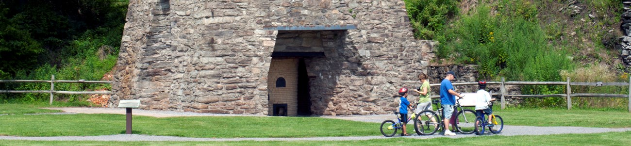 39 On The Land Header A family on bicycles reads information at a historic site.