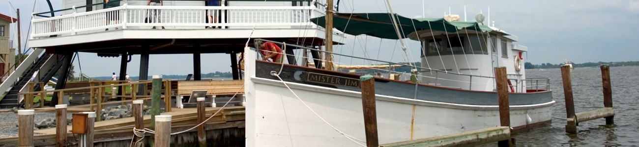 41 History & Heritage Header A skipjack docked beneath a restored and relocated screw pile lighthouse.
