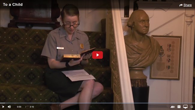 Screencap of a video, showing a ranger seated reading poetry