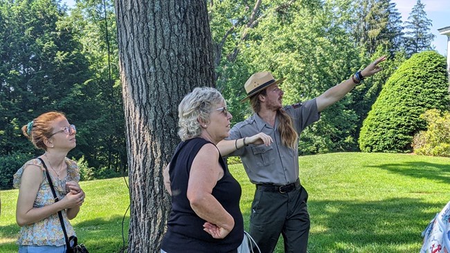 Park Ranger talks to two visitors and points in the distance