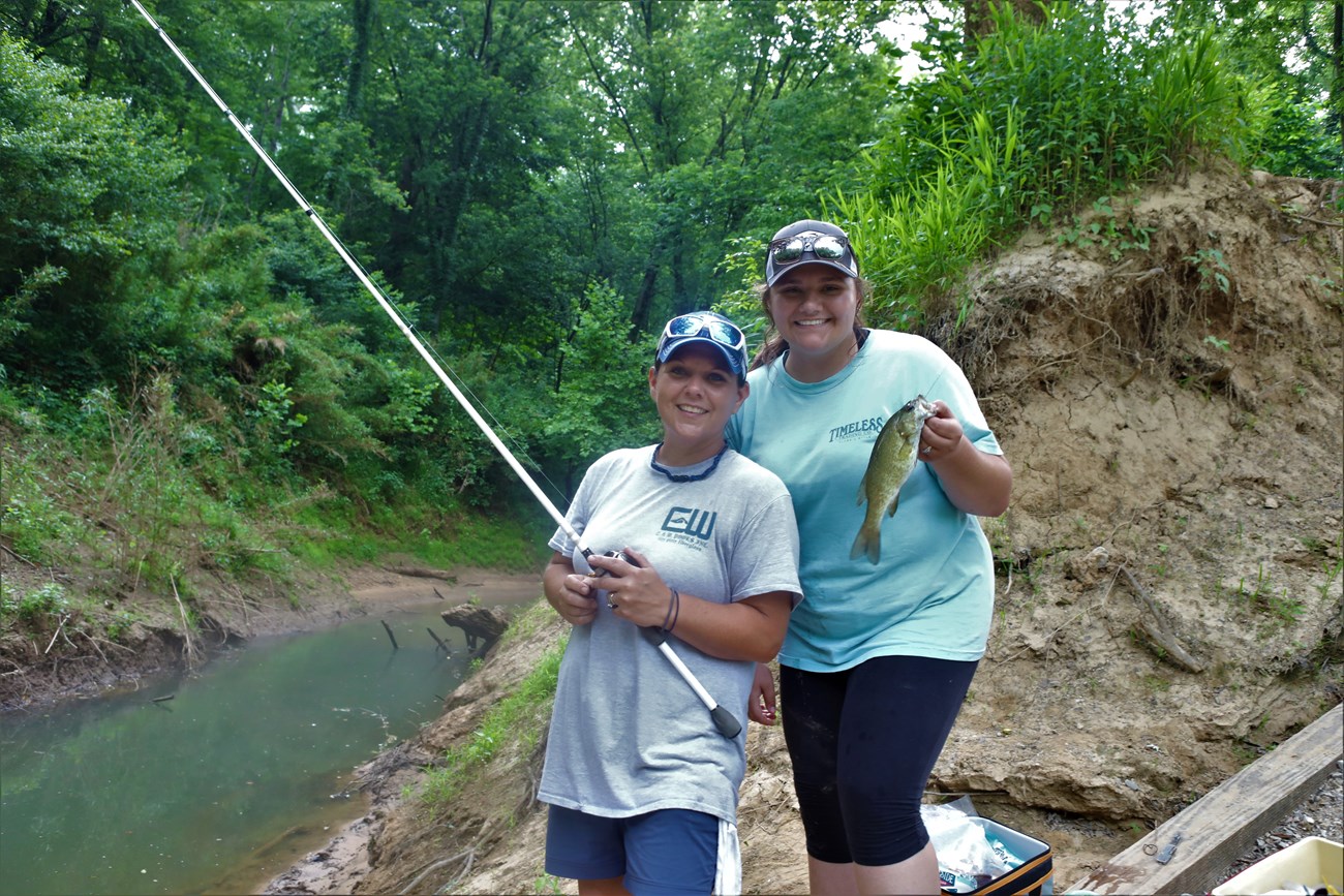 Two park visitors hold up a fish they just caught in the river.