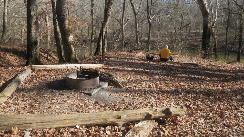 A backpacker sits near a scenic overlook while visiting the White Oak Campsite.