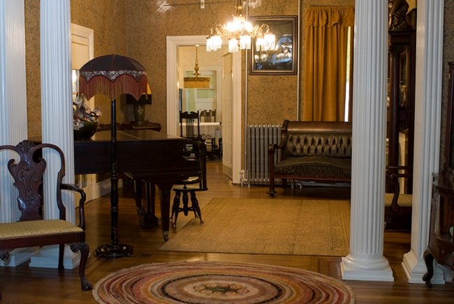 Interior parlor of a turn of the century house, with columns, chandelier, and a horse hair sofa.