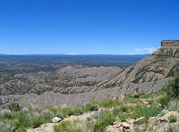 Landscape view of soft grey mounds of earth with snowcapped peaks in the distance