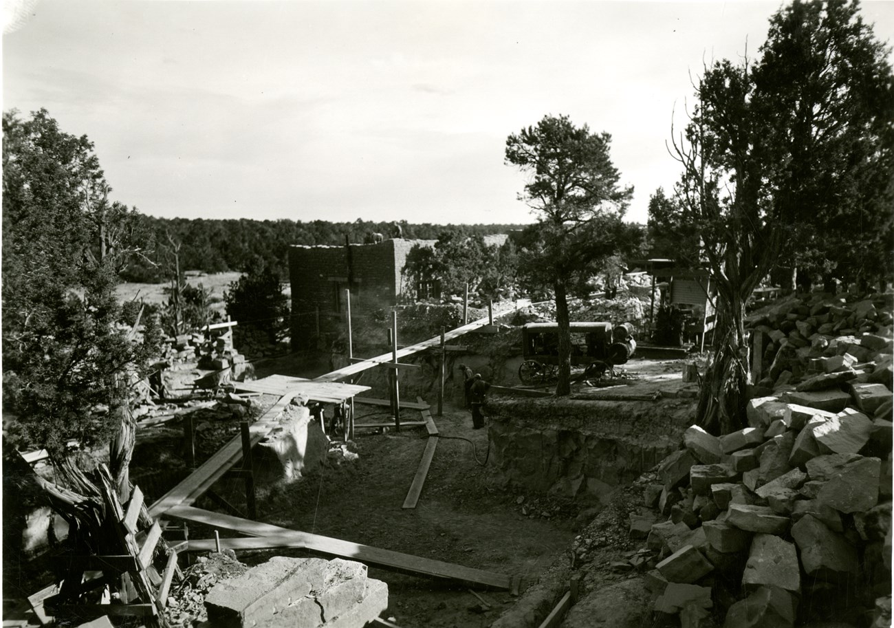 Historic black-and-white photo of museum construction site: dug foundation, piles of sandstone blocks, wood scaffolding