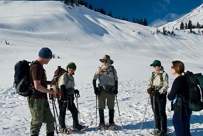 Volunteer snowshoe rovers are helping snowshoeing visitors on a sunny winter day.