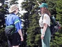 A meadow rover volunteer is talking to a visitor on a trail in the Paradise area.