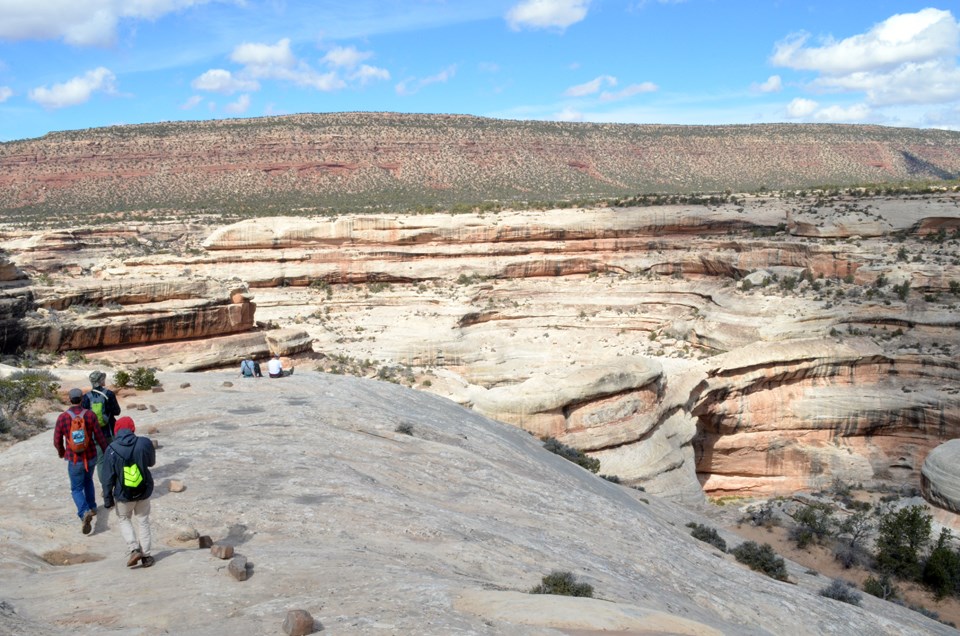 hikers walking over slickrock near Sipapu natural bridge