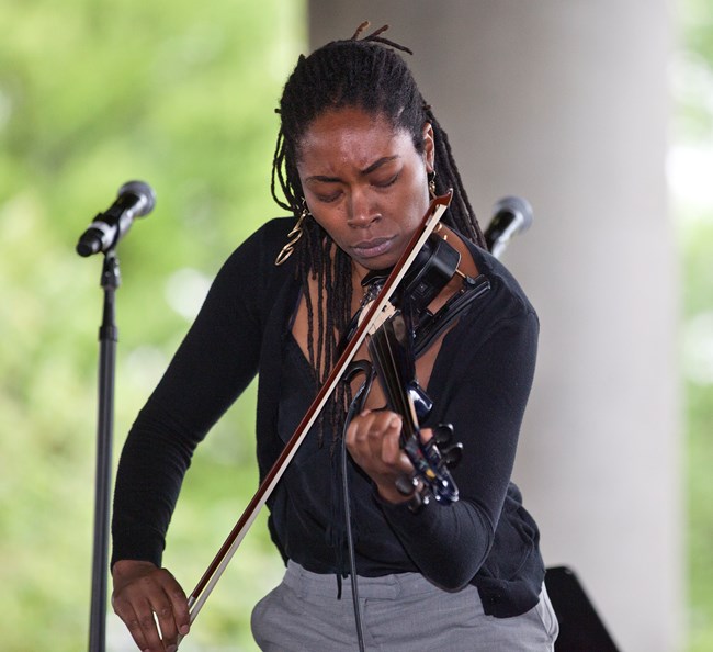 A woman plays violin in the park.