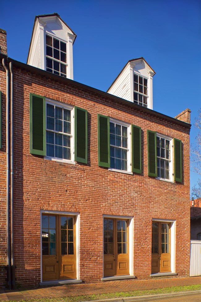 two and a half story brick building with three bay facade and two dormer windows