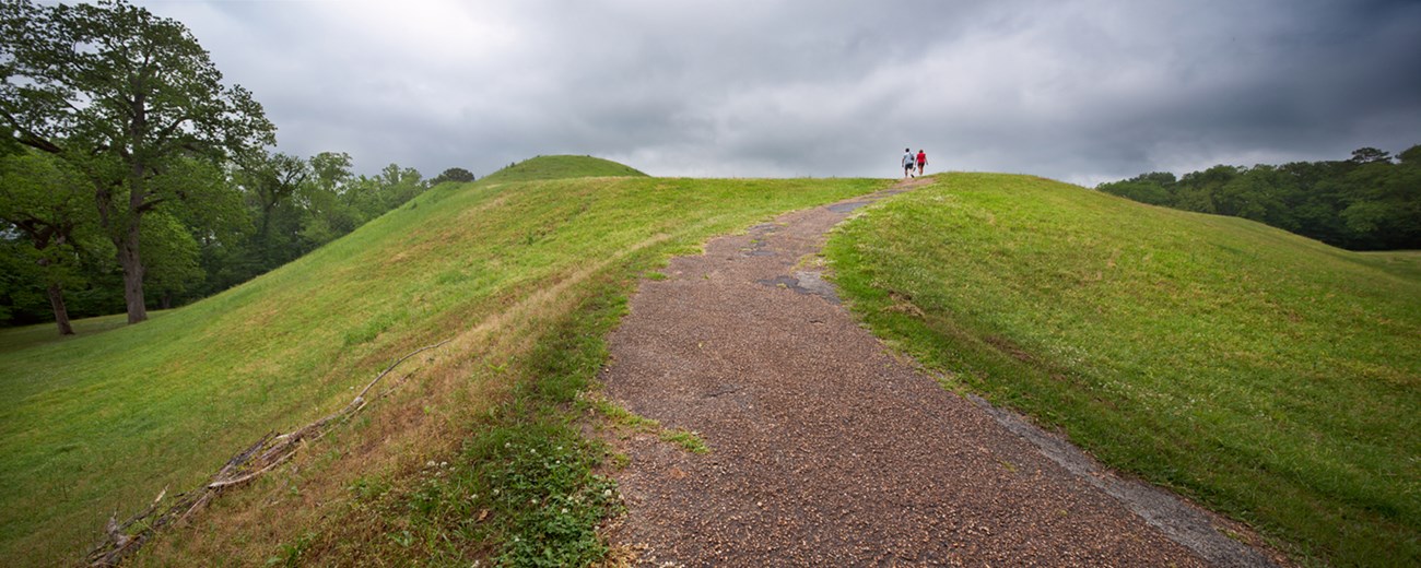 paved trail leading to the top of Emerald mound. Green grass is on both side of paved trail.