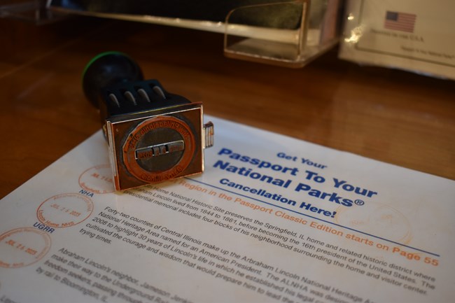 A rubber stamp labeled "New Philadelphia National Historic Site" with date lies on a counter top.