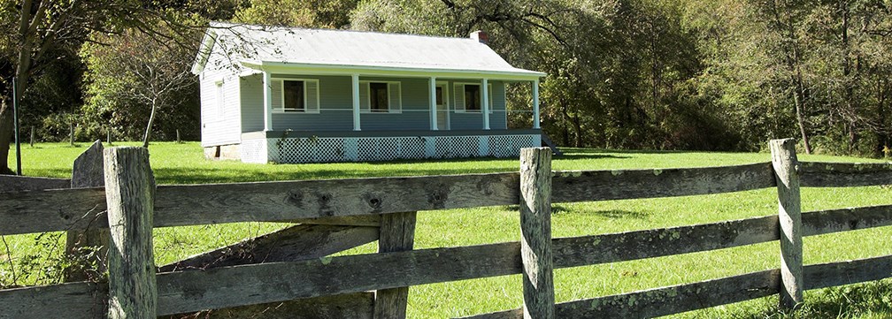 farmhouse behind split rail fence