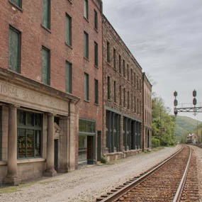 Three large brick buildings next to each other along railroad tracks. The closest building has a stone front facade that says Bank of Thurmond