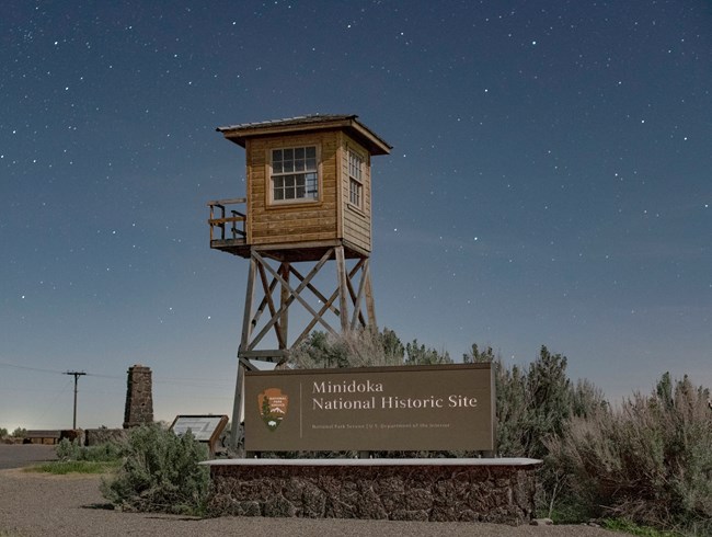 The Minidoka entrance sign and replica guard tower at night.