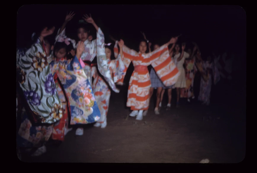 A line of young girls holding their hands up in the air while wearing colorful kimonos. A line of young girls holding their hands up in the air while wearing colorful kimonos.