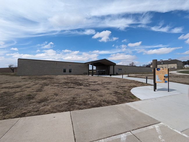 Tallgrass Prairie Visitor Center with brown grass in front and blue sky behind.