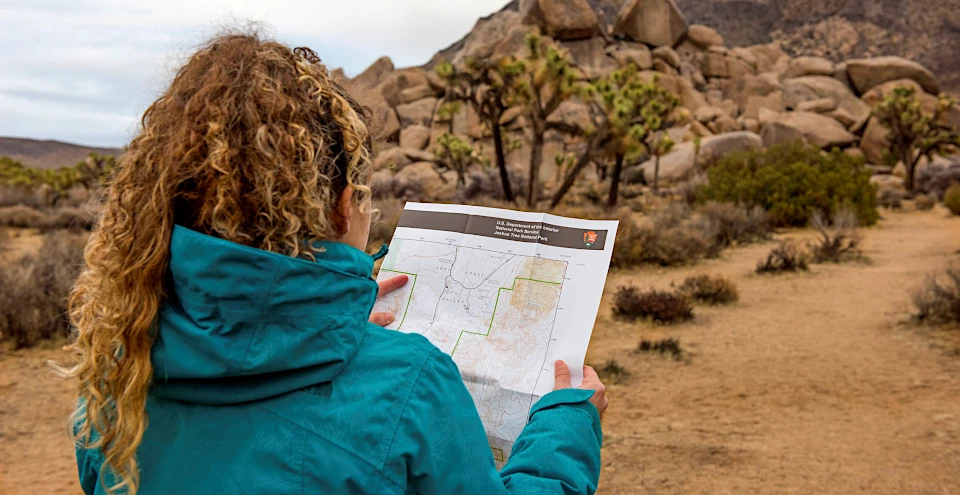 Visitor looking at Map in JOTR Women studying map in desert landscape