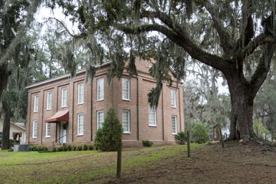 a brick building underneath a large oak tree