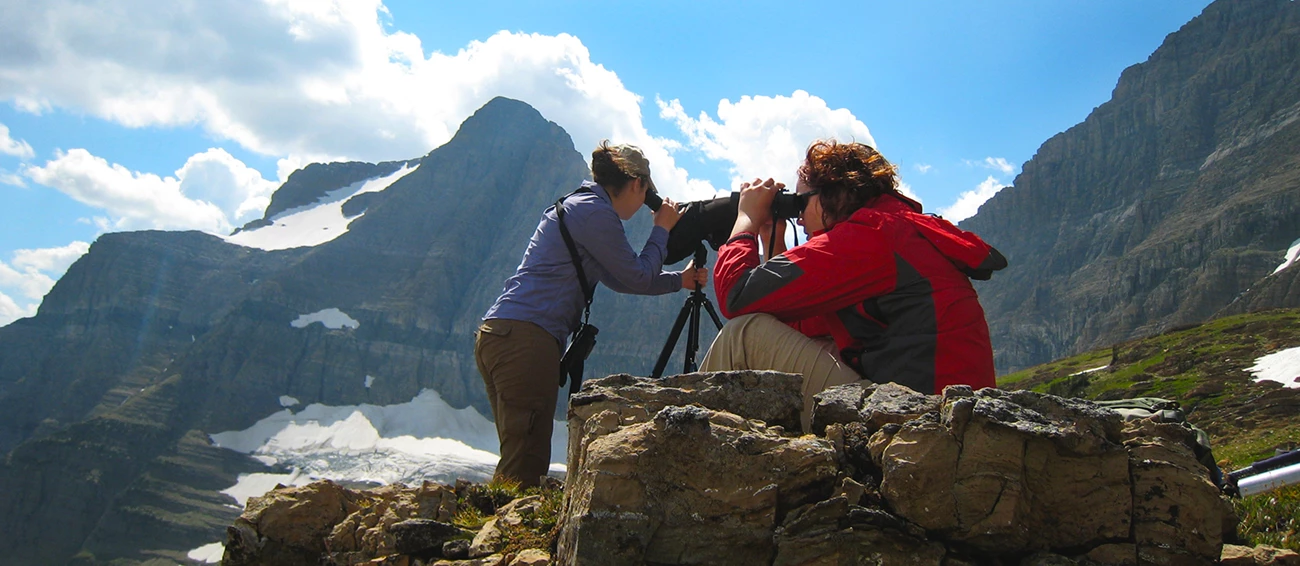 CCRLC staff2 Two women scan mountainside for mountain goats; one looks through scope, the other through binoculars.
