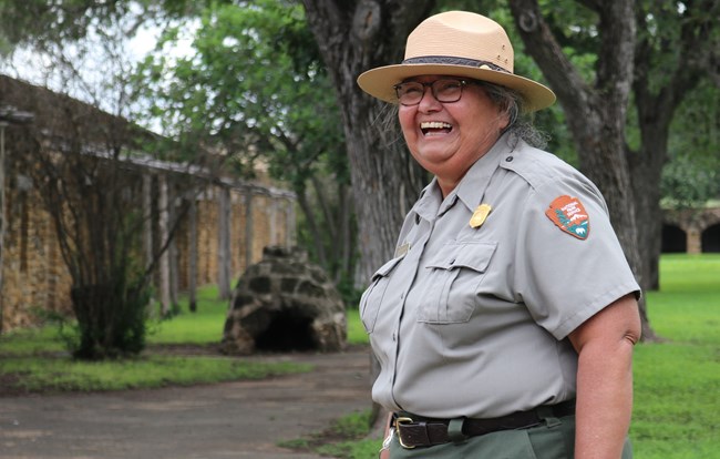 Female Park Ranger smiles joyously as she walks through Mission San Jose.