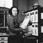 A woman standing in front of a file cabinet.