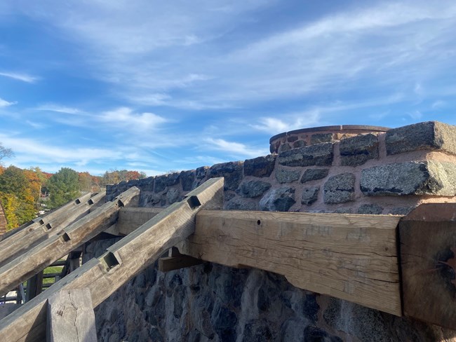 Large wooden beams form the outline of a roof for a historic blast furnace