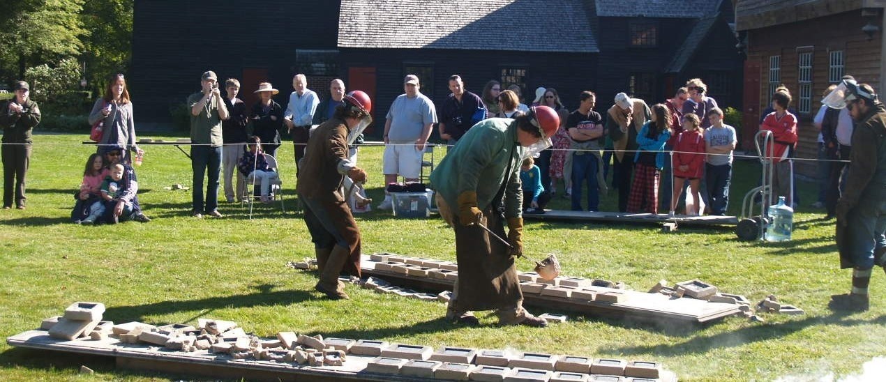 Park visitors watch behind a roped off area as professionals pour molten iron into molds.